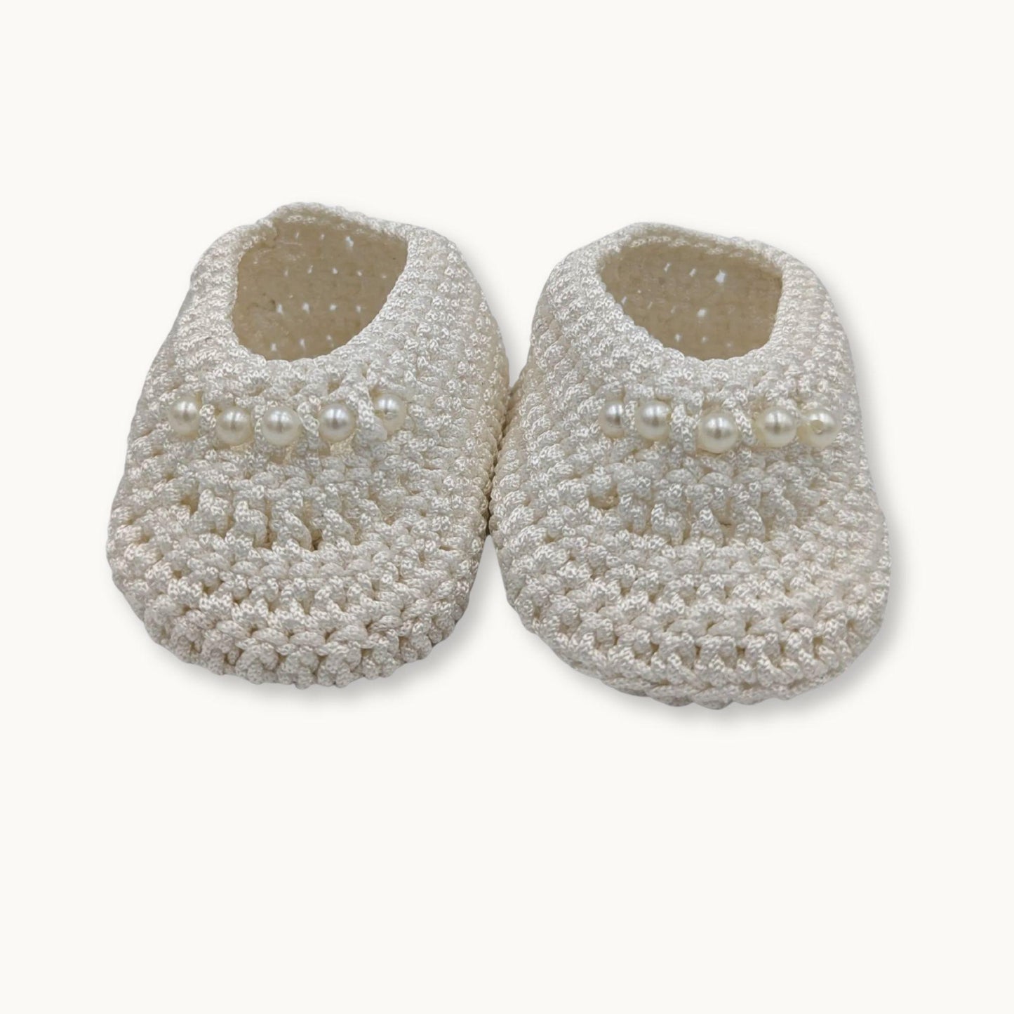 Pair of textured slippers with pearl-like embellishments on a white background