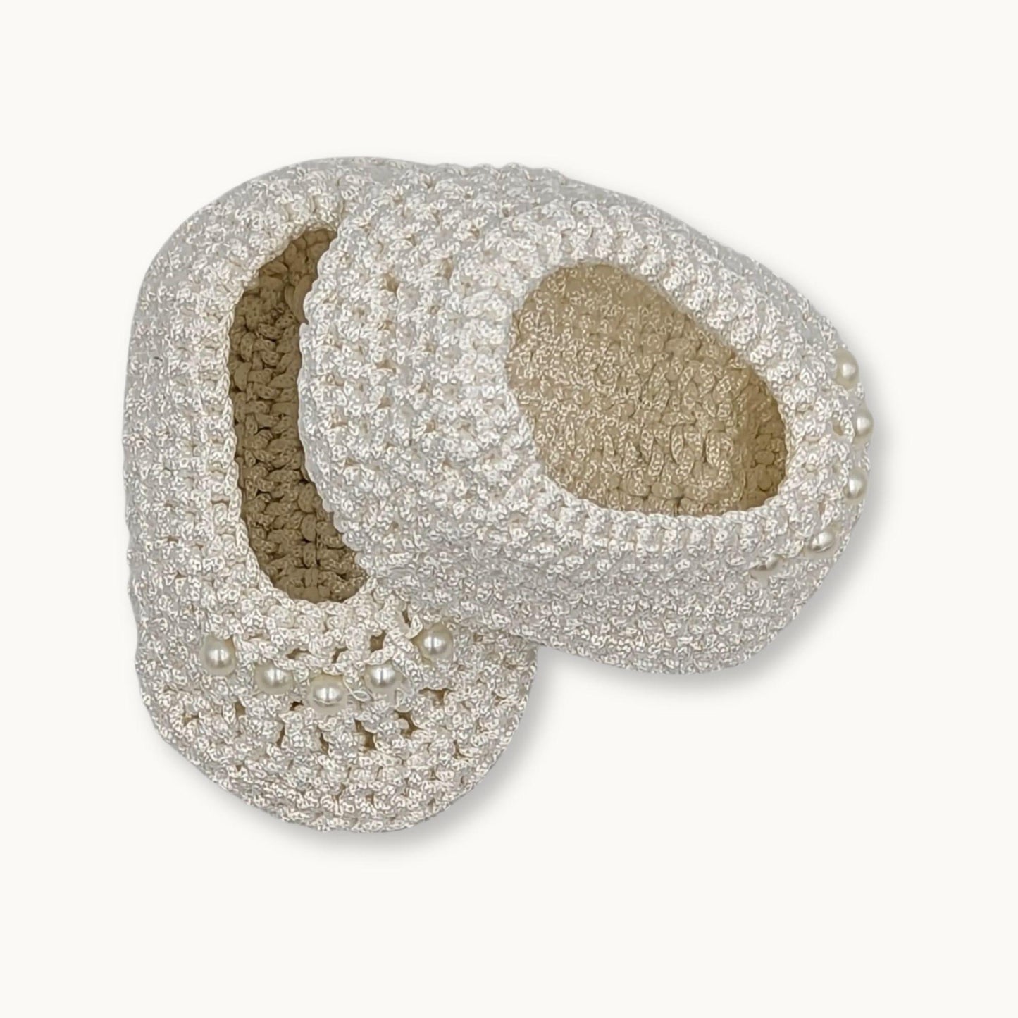 Pair of decorative slippers with pearl embellishments on a white background